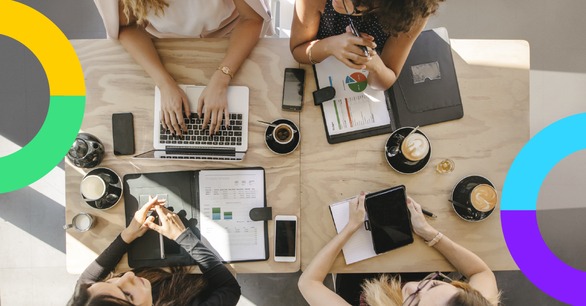 a group of people sitting around a table with electronics and a computer